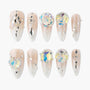 Long almond-shaped press-on nails with nude ombré base, rhinestones, 3D crystal accents, and pearl details