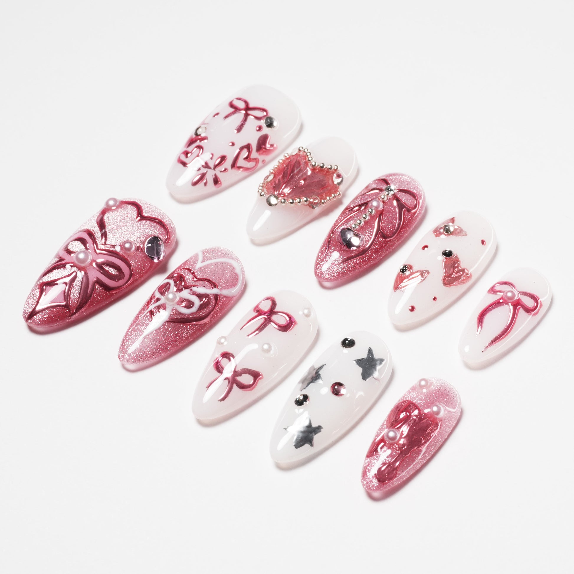 Handmade press-on nails with pink and white bow designs, glitter, pearls, and rhinestones