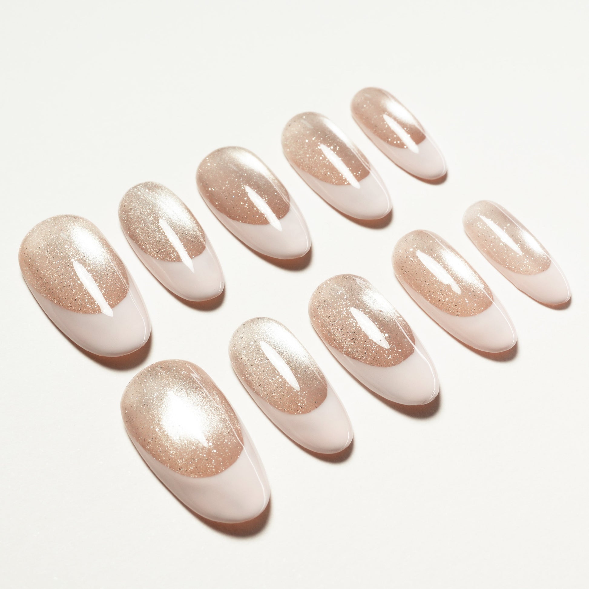 Oval-shaped nude and glitter gradient press-on nails displayed on white background