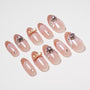 Handmade press-on nails with nude pink base, rhinestone and gold bow accents