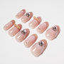 Handmade pink press-on nails with rhinestones, gold bows, and pearl accents, arranged on white background.