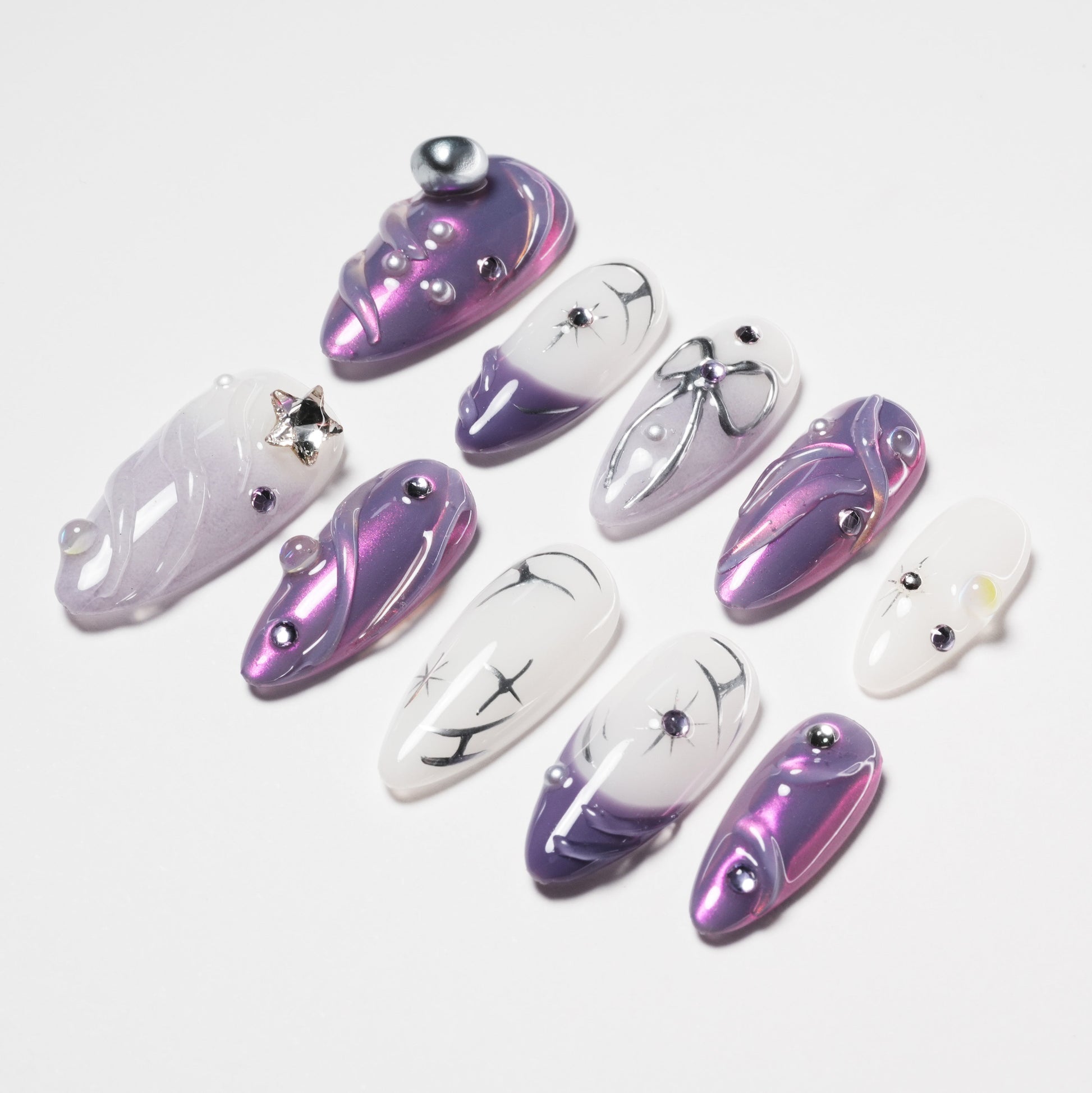 Handmade press-on nails in purple and white with star, bow, and gemstone accents