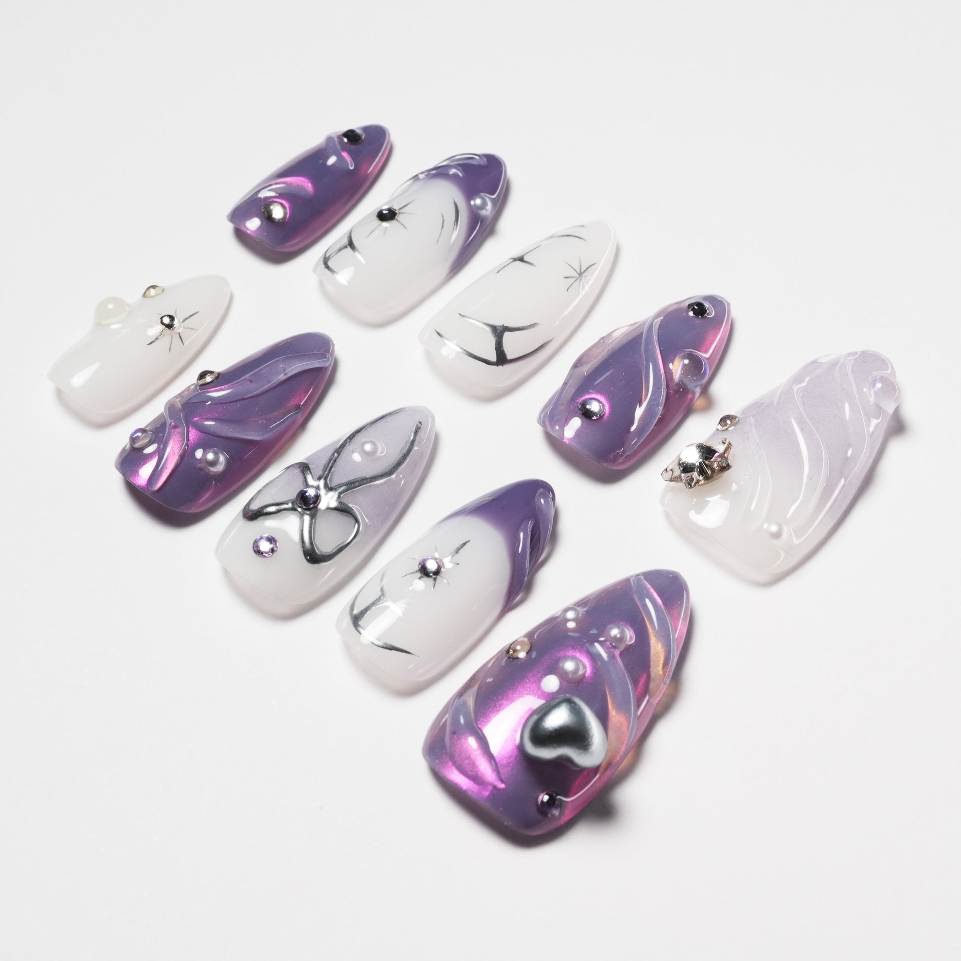 Purple and white press-on nails with butterfly, pearl, and gem accents, glossy finish