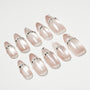 Set of glossy nude press-on nails with silver rhinestone accents, arranged on white background