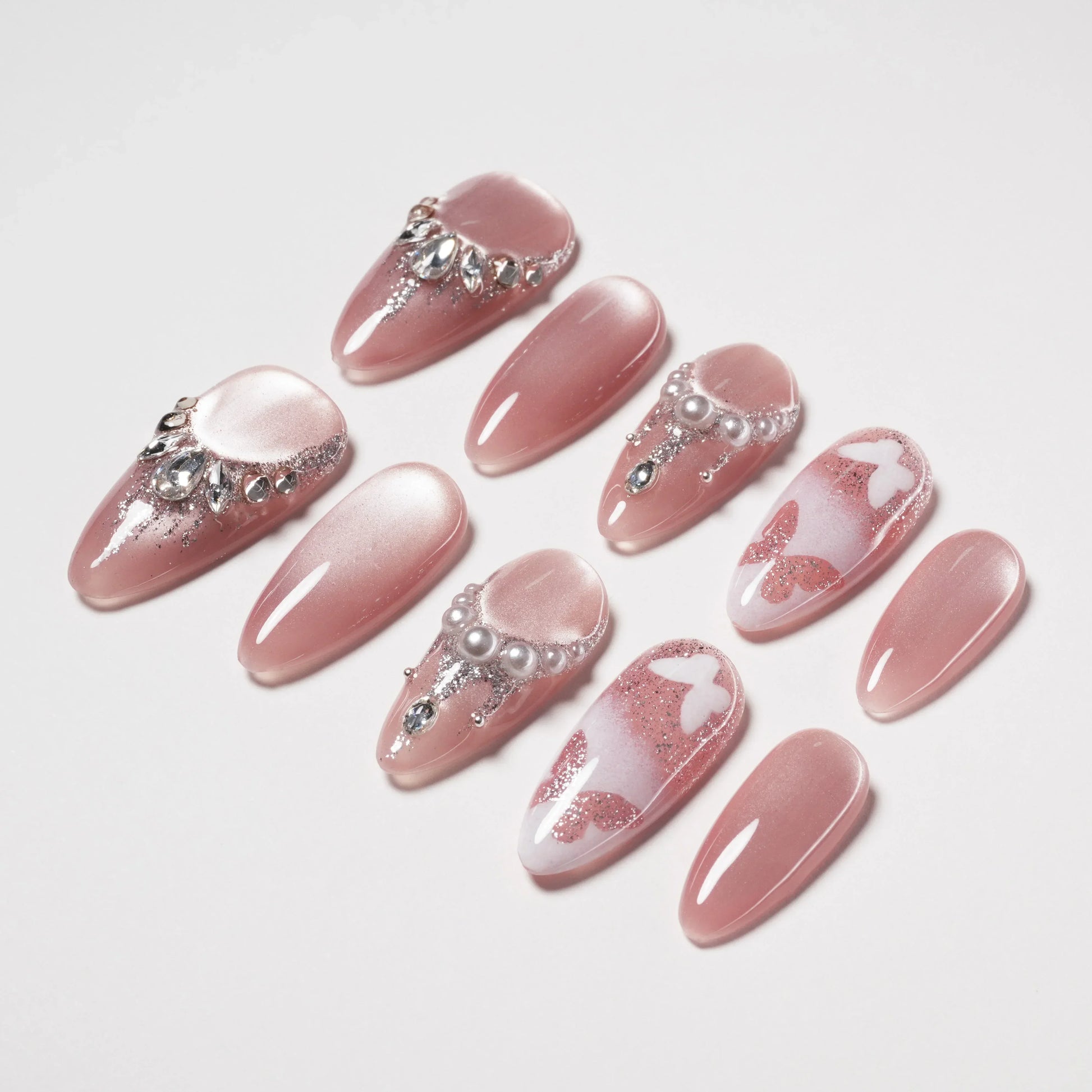 Elegant pink press-on nails with rhinestone, pearl, glitter, and butterfly decorations