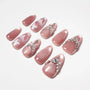 Pink handmade press-on nails with rhinestones, pearls, and glitter accents on white background