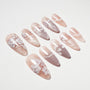 Handmade pink press-on nails with white floral designs and glossy finish