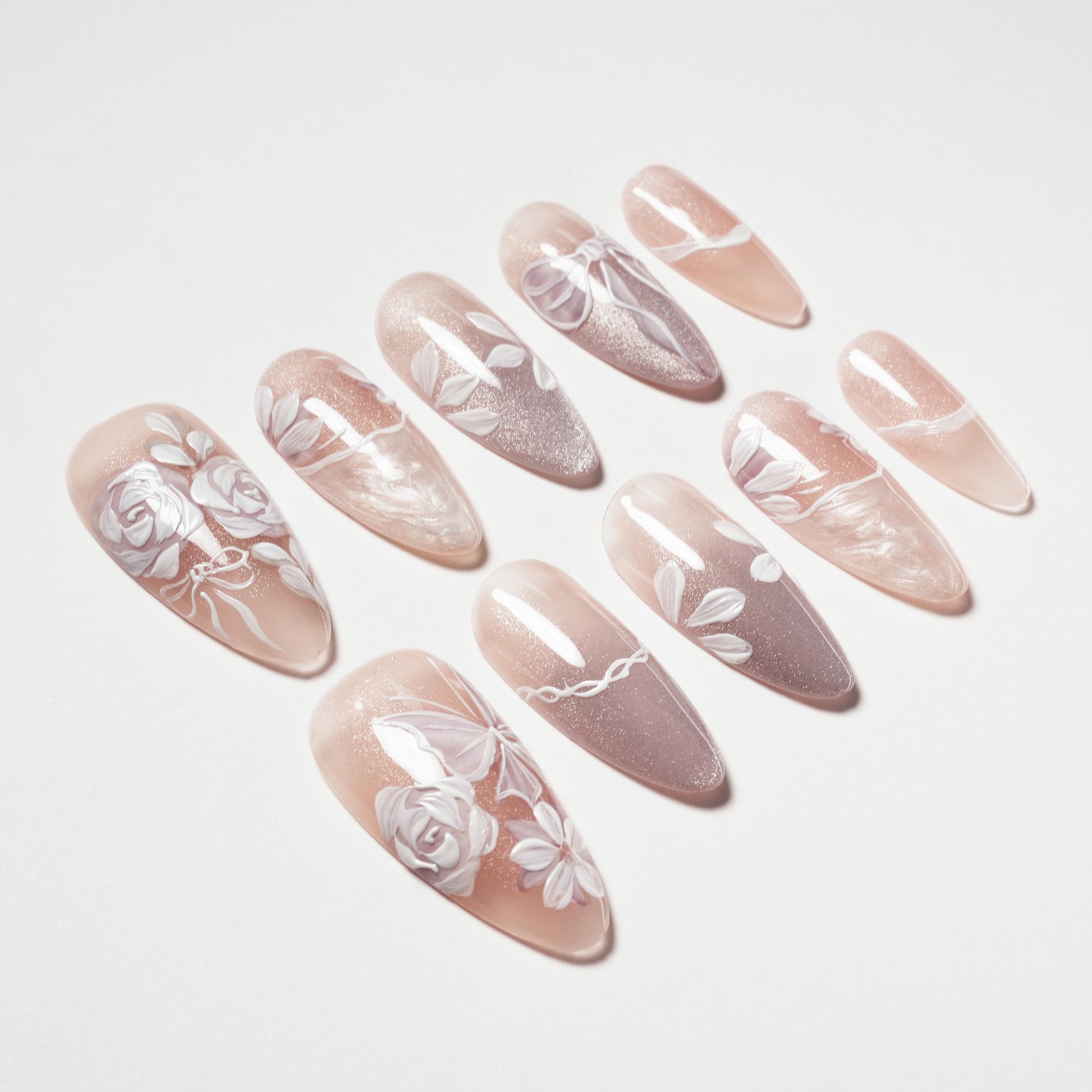 Handmade pink press-on nails with white floral designs and glossy finish