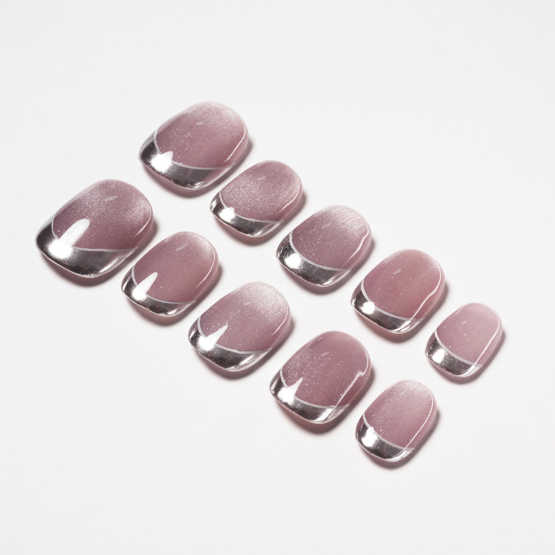 Glossy pink press-on nails with silver chrome tips arranged on a white background