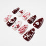 Red and white press-on nails with abstract patterns, pearls, and rhinestone accents