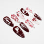 Handmade press-on nails in red and white with hearts, bows, pearls, and gemstone accents