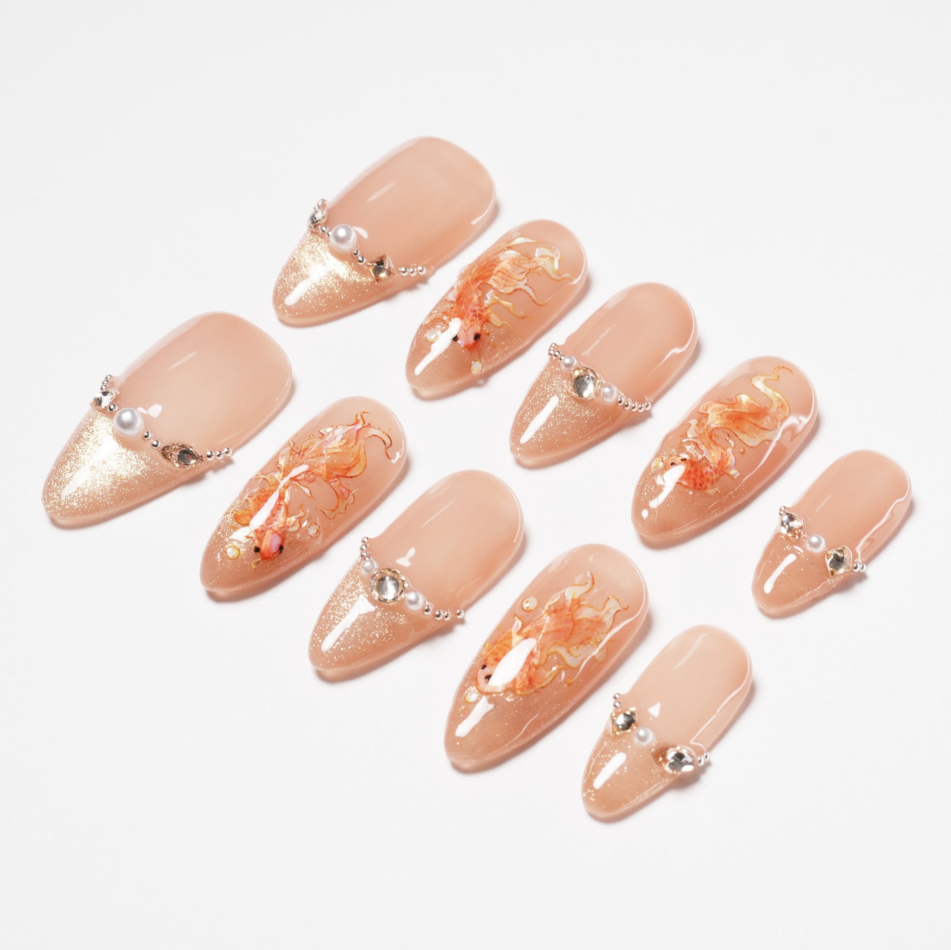 Handmade press-on nails with nude base, gold glitter, 3D rhinestones, and orange floral art.