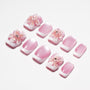 Pink and white press-on nails with 3D floral designs and rhinestone accents on a white background