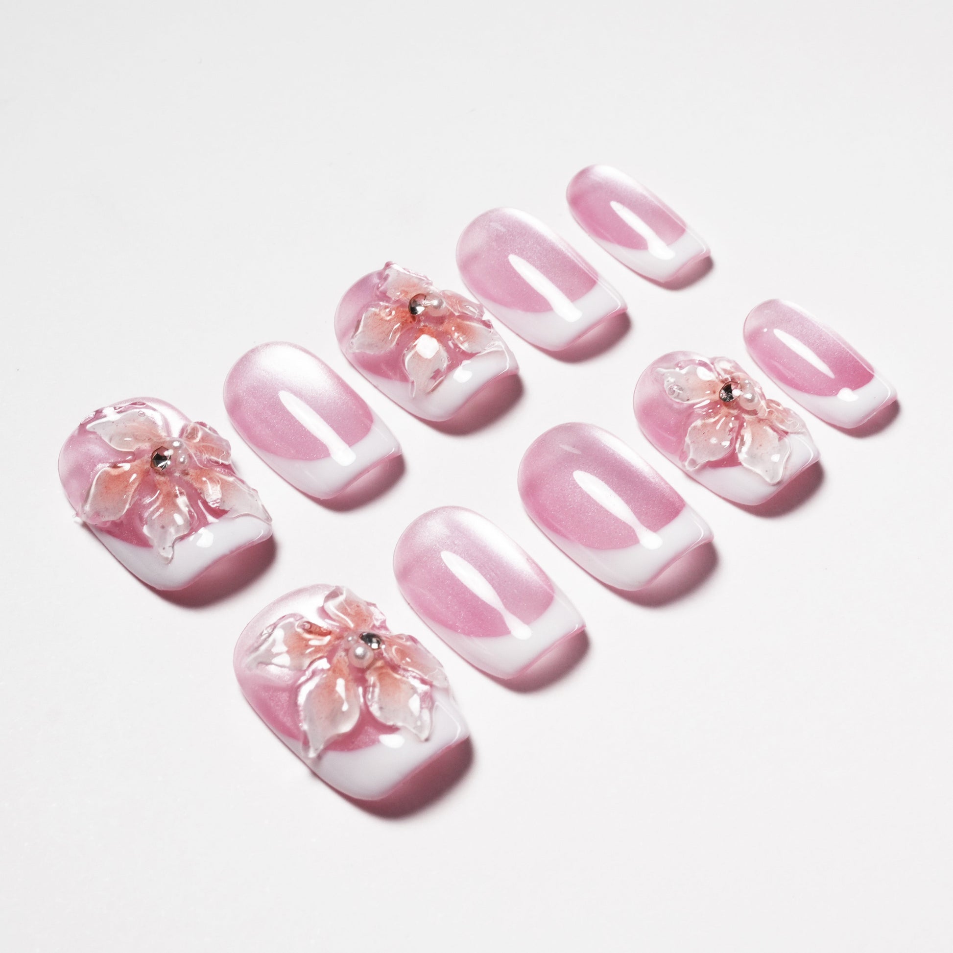 Pink and white press-on nails with 3D floral design and rhinestone accents