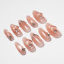 Glossy nude pink press-on nails with heart and silver rhinestone accents on white background