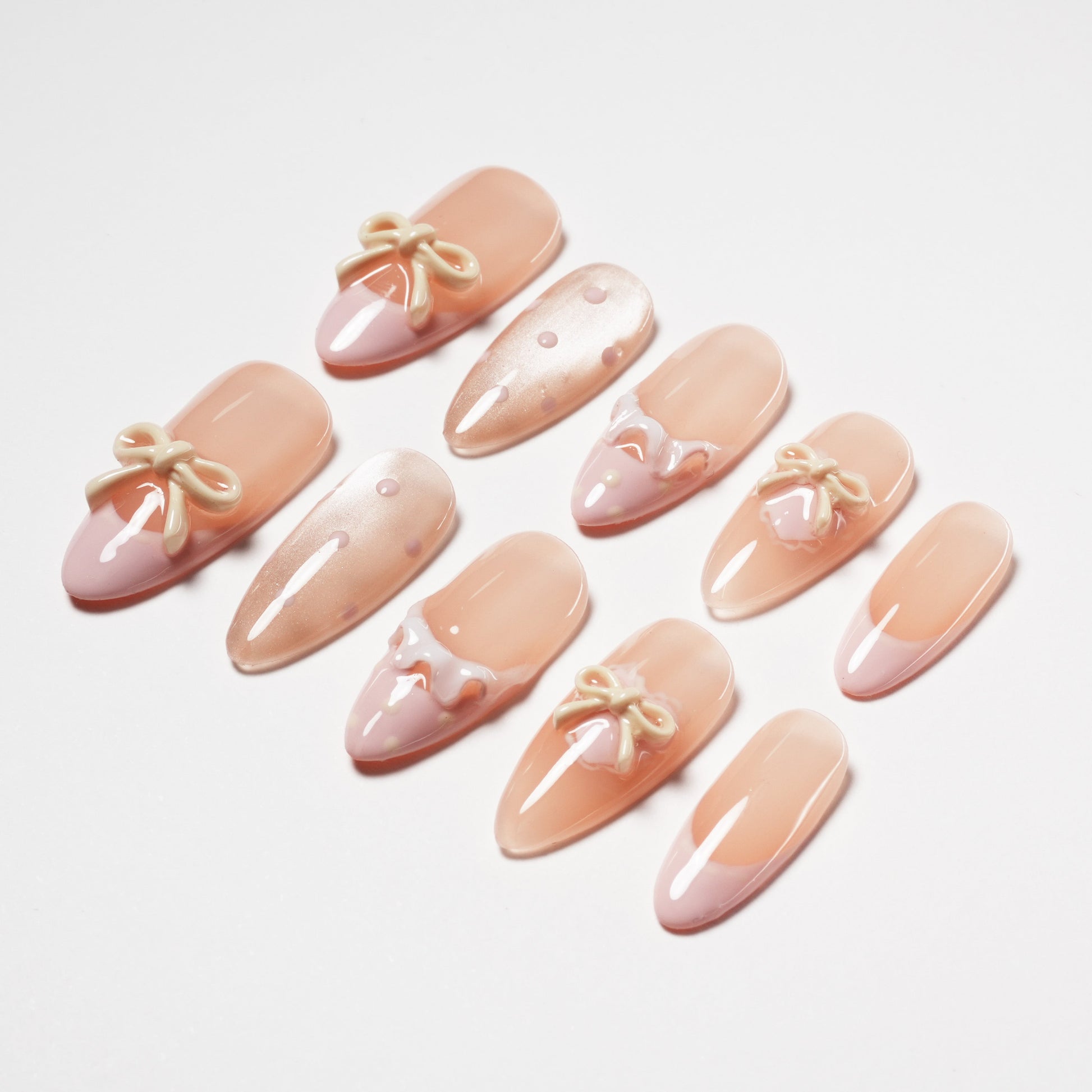 Handmade press-on nails in nude pink with 3D bows, polka dots, and French tip designs