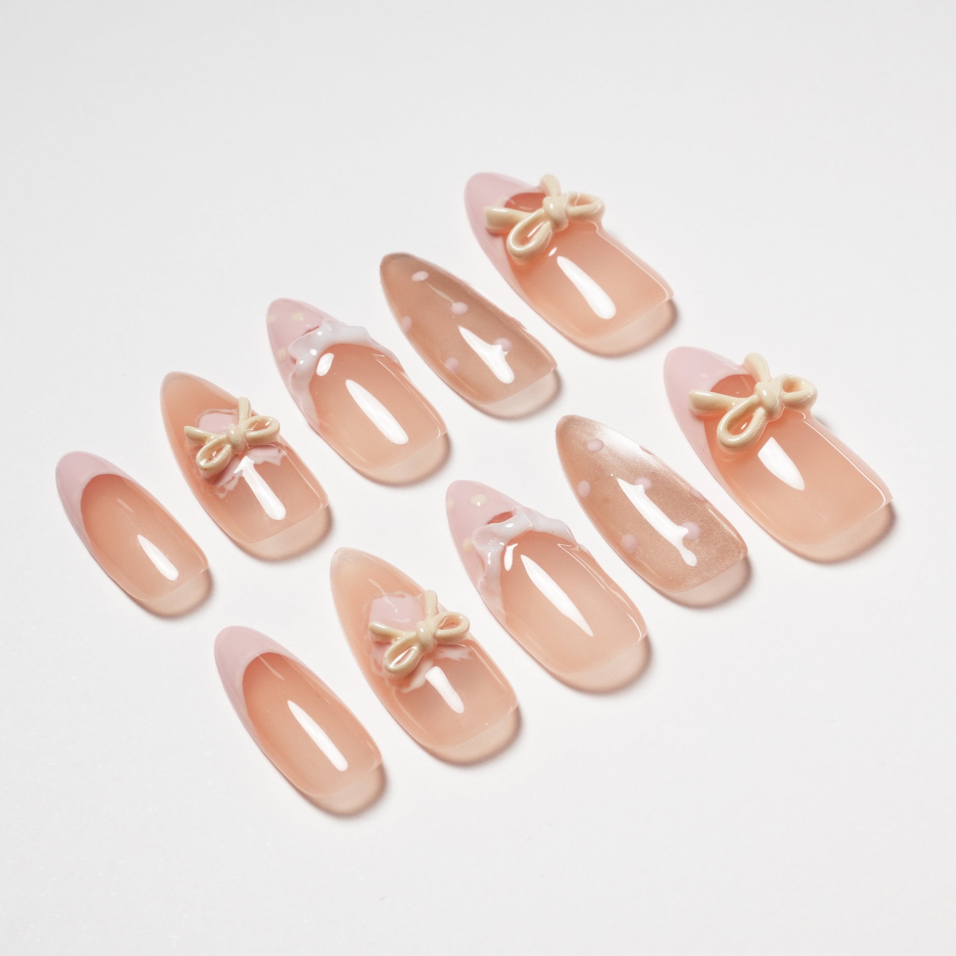 Handmade press-on nails in nude pink with 3D bows and playful polka dot designs