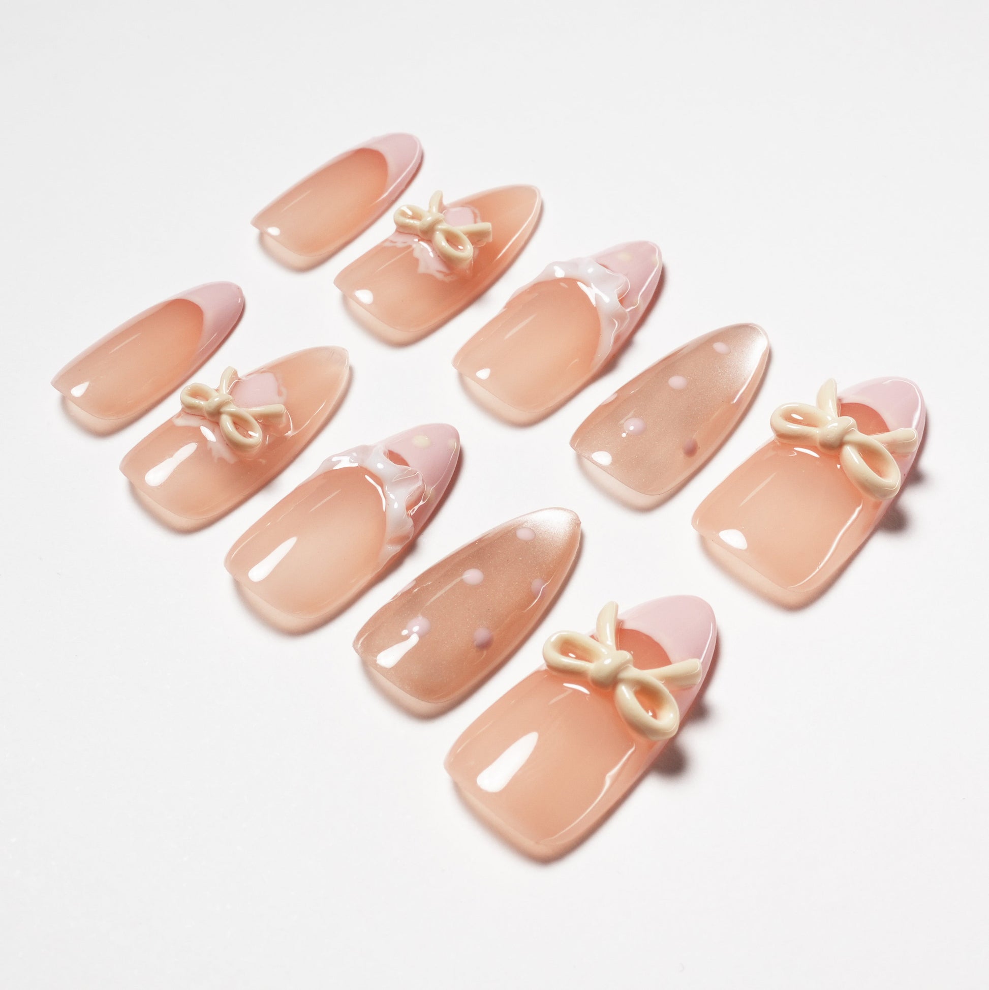 Handmade nude press-on nails with pink tips, polka dots, and 3D bow accents