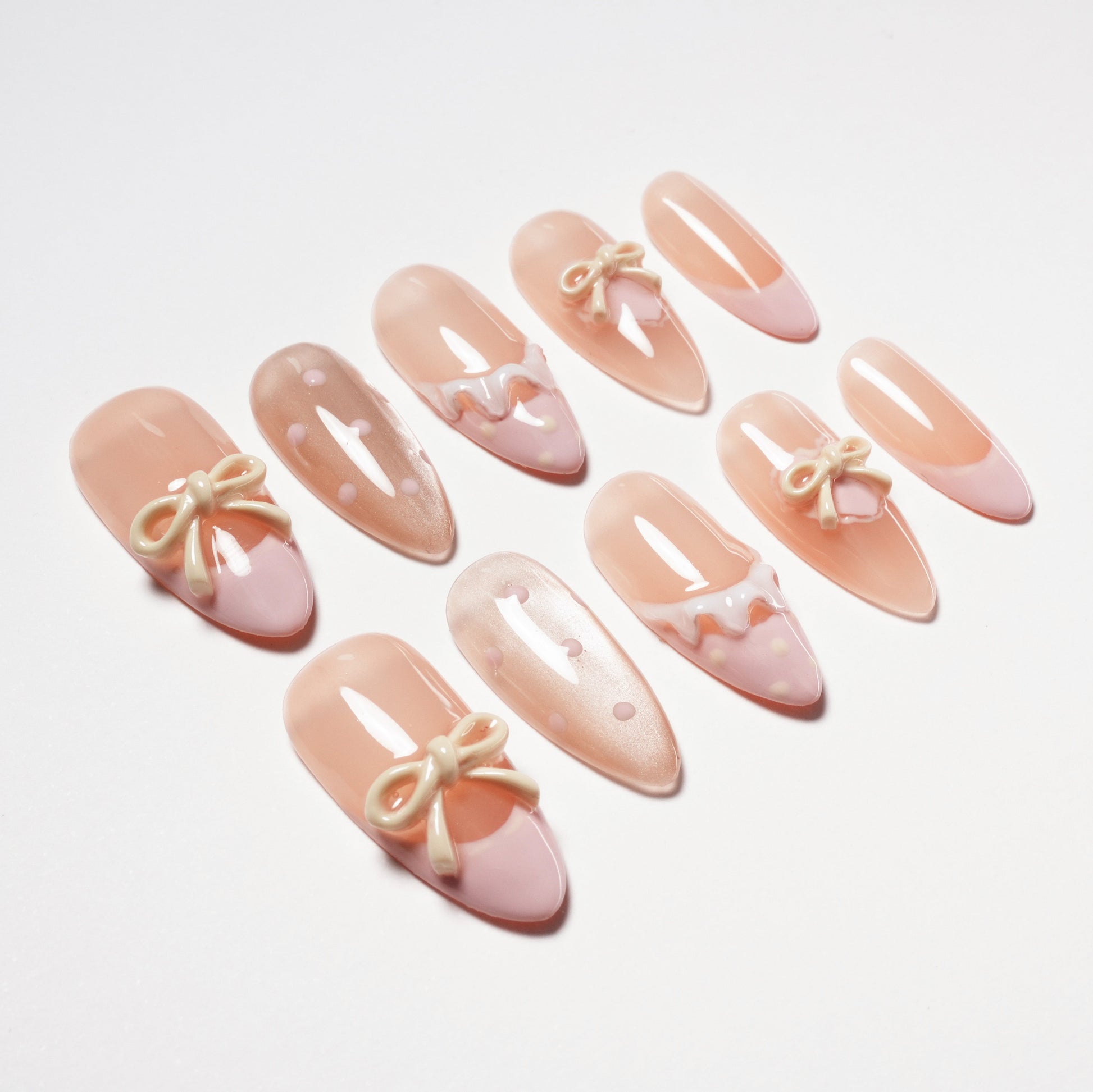 Handmade pink press-on nails with pastel bows, polka dots, and scalloped designs