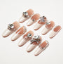 Long coffin press-on nails with nude and white French tips, embellished with large crystal rhinestones and pearls.