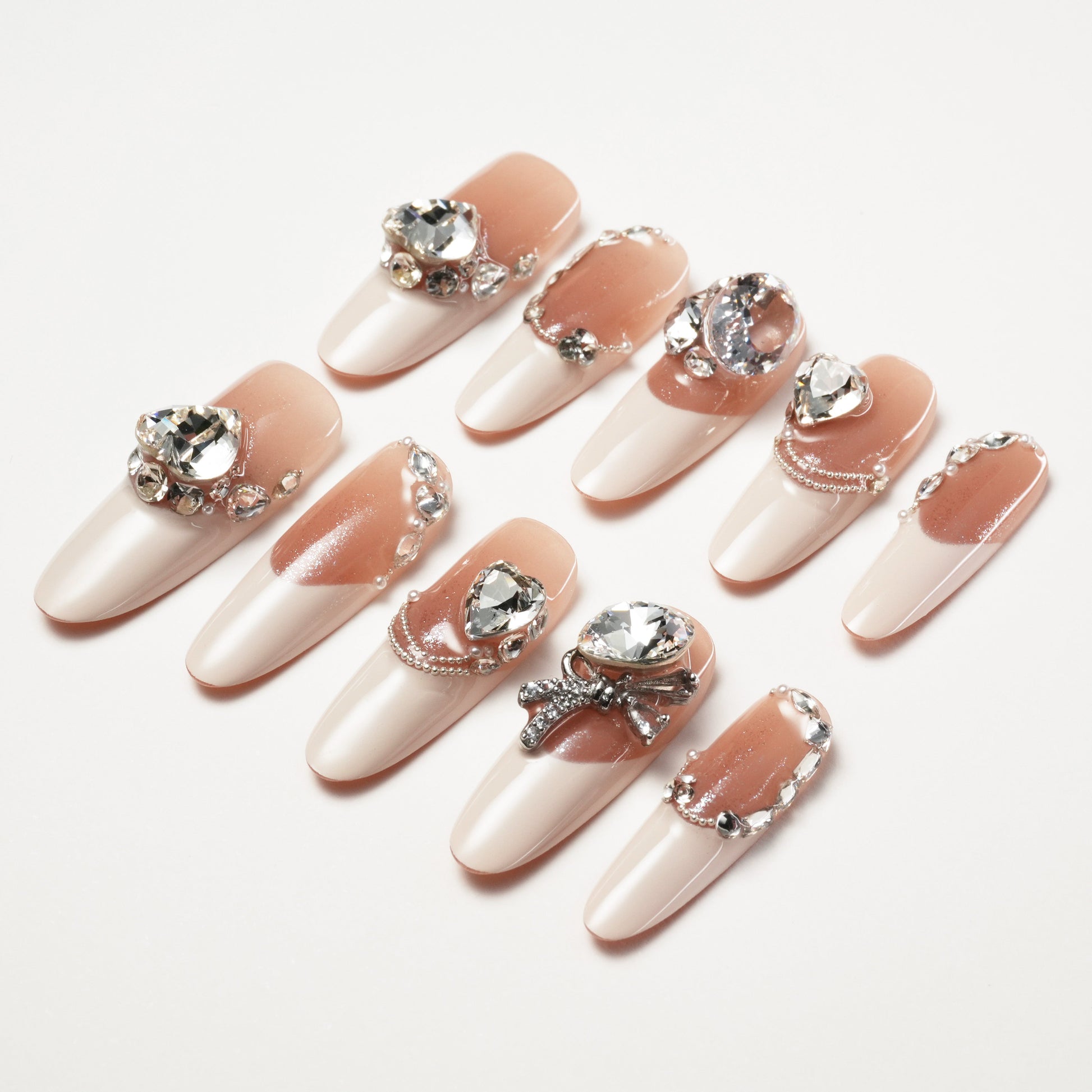 Long coffin press-on nails with nude and white French tips, embellished with large crystal rhinestones and pearls.