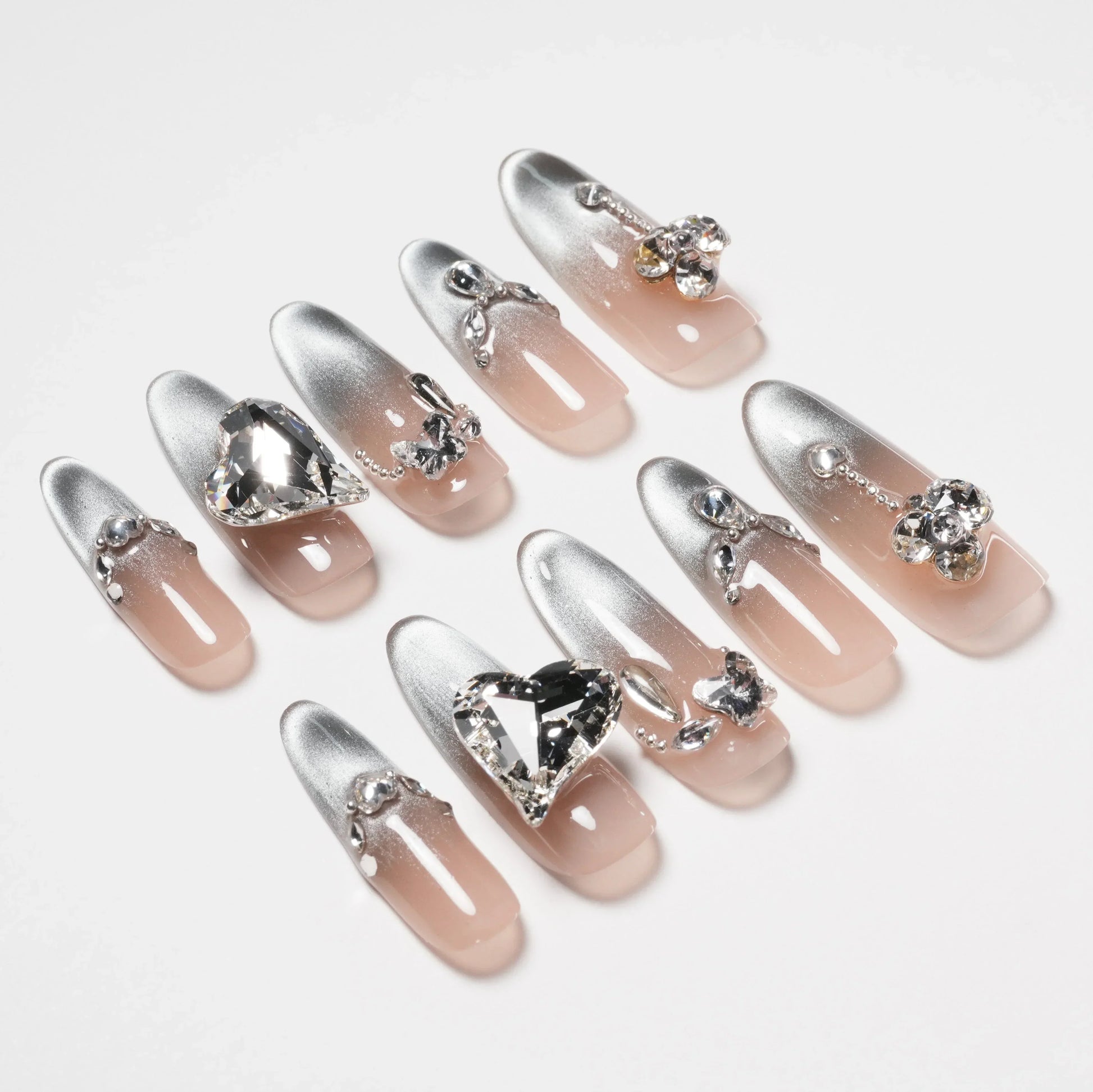 Silver ombre press-on nails with 3D rhinestone and jewel accents on a white background