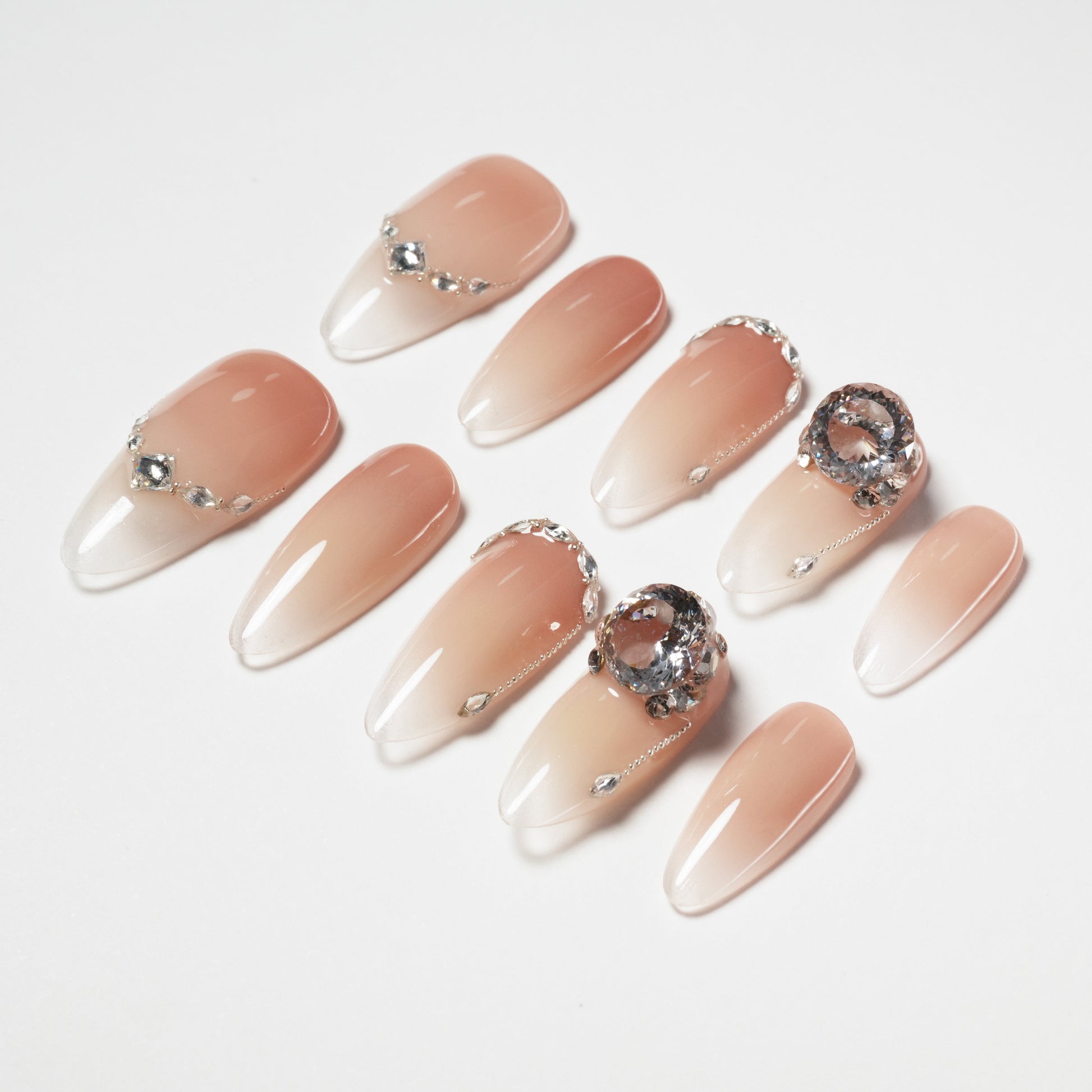 Nude ombre press-on nails with rhinestone and crystal accents, stiletto shape
