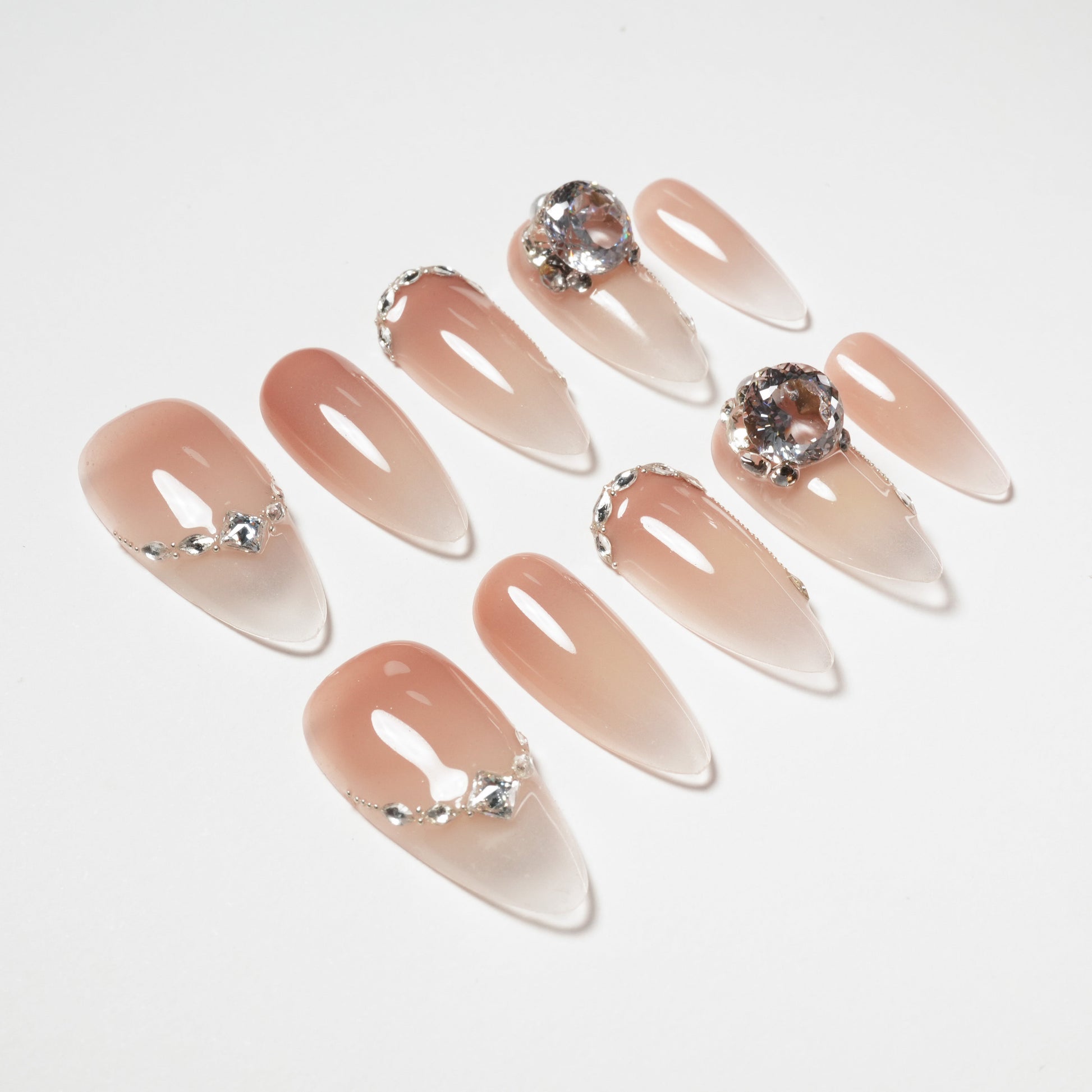 Glossy nude ombre press-on nails with silver accents and large crystal embellishments