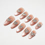 Almond-shaped nude press-on nails with rhinestone crystal accents on a white background.