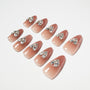 Glossy nude ombre press-on nails with large rhinestone gem accents, arranged on white background