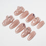Set of glossy nude pink press-on nails with 3D bow designs and rhinestone accents