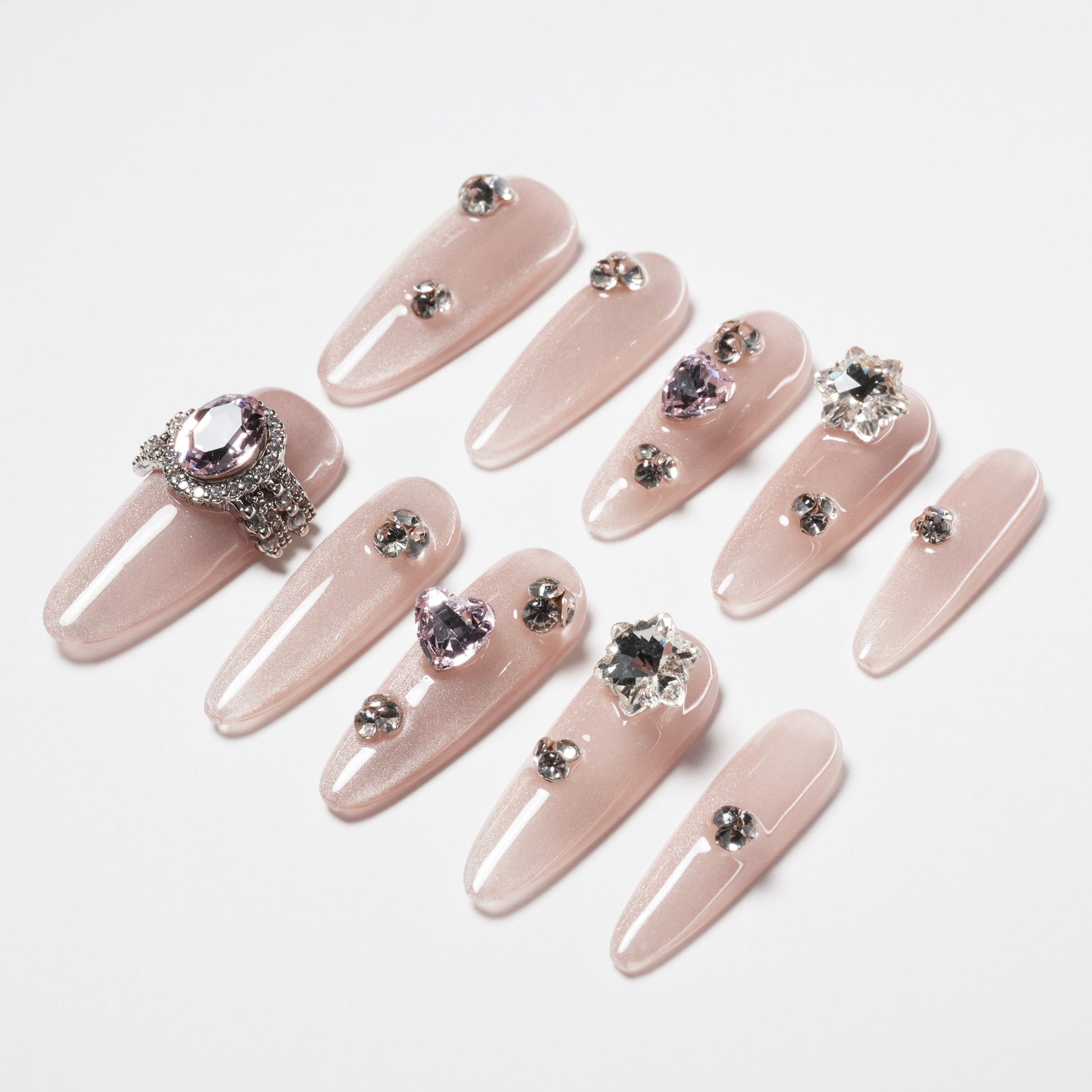 Set of long, nude pink press-on nails with rhinestone and gemstone embellishments