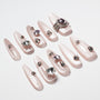 Shimmery pink press-on nails with rhinestone and crystal gem accents, arranged on white background