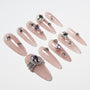 Glossy nude press-on nails decorated with silver rhinestones and large pink gemstone accents