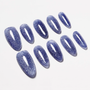 Set of handmade press-on nails in almond shape with glittery blue finish on white background