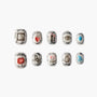 Handmade press-on nails with silver borders and unique art designs including hearts, eyes, and symbols.