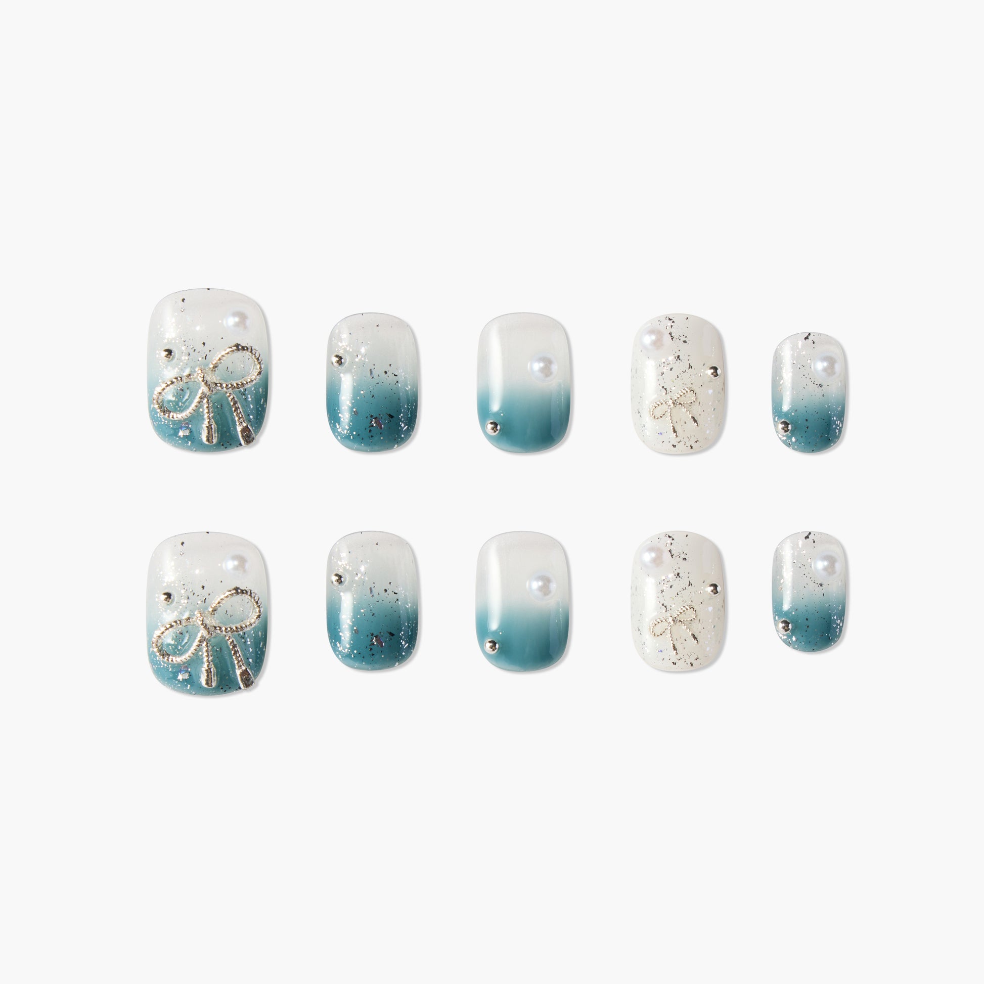 Blue ombre press-on nails with gold bow accents, pearls, and glitter details, arranged on white background.