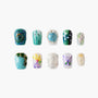Assorted handmade press-on nails with blue, green, floral, butterfly, and glitter designs