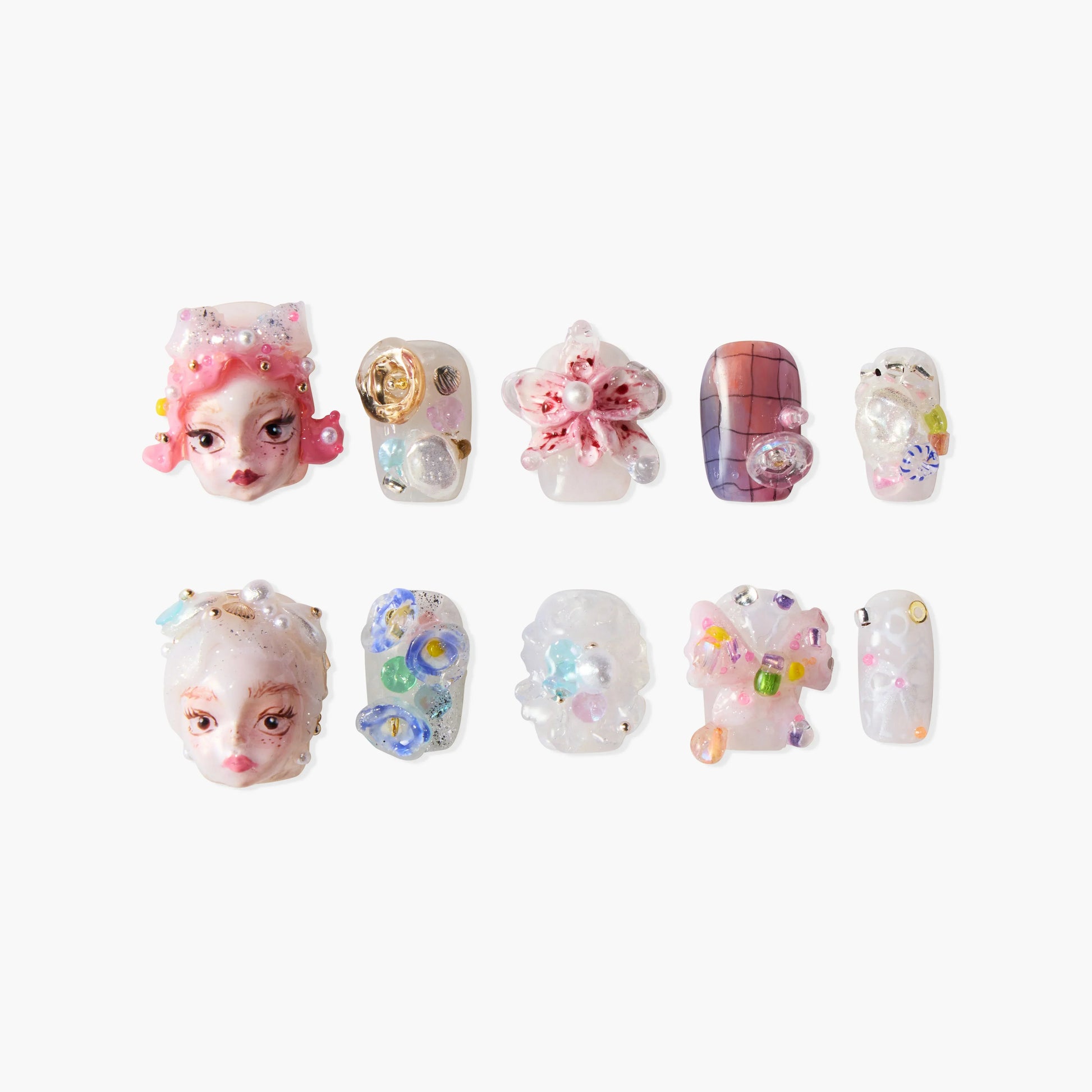 Handmade press-on nails with 3D designs, colorful gems, floral and face art accents on white background.