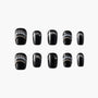 Black press-on nails with pearl and chain accents, arranged on a white background.