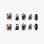 Black and white butterfly press-on nails with ombre, glitter, and abstract designs
