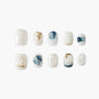 Handmade press-on nails with white, gold, and blue marble and pearl accents, arranged on white background