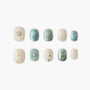Handmade press-on nails in teal and ivory with pearl, flower, and gold foil accents.