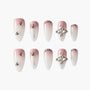 Ombre pink and white press-on nails with rhinestones, glitter, and 3D silver embellishments