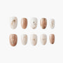 Handmade press-on nails in nude, white, marble, and gold foil designs displayed on white background