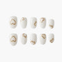 Set of white press-on nails with metallic gold heart designs on each nail, displayed on white background