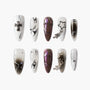 Handmade press-on nails set with black, white, and metallic designs, cross and star charms