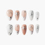 Handmade press-on nails with nude and white base, silver bows, stars, and pearl accents