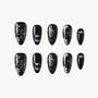 Black press-on nails with blue floral designs, gold accents, and pearl embellishments