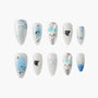 Handmade press-on nails with blue and white designs, bows, hearts, and 3D bunny art.